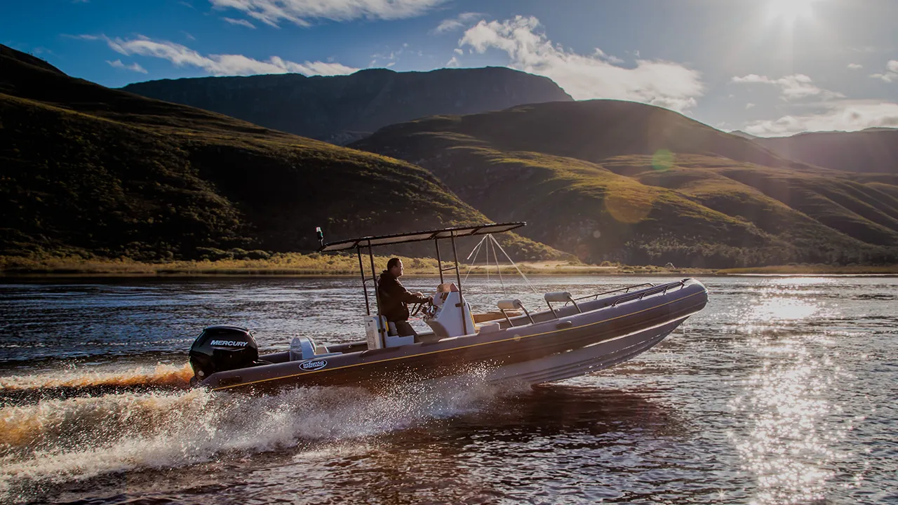 Inflatable boat speeding across the water at sunset