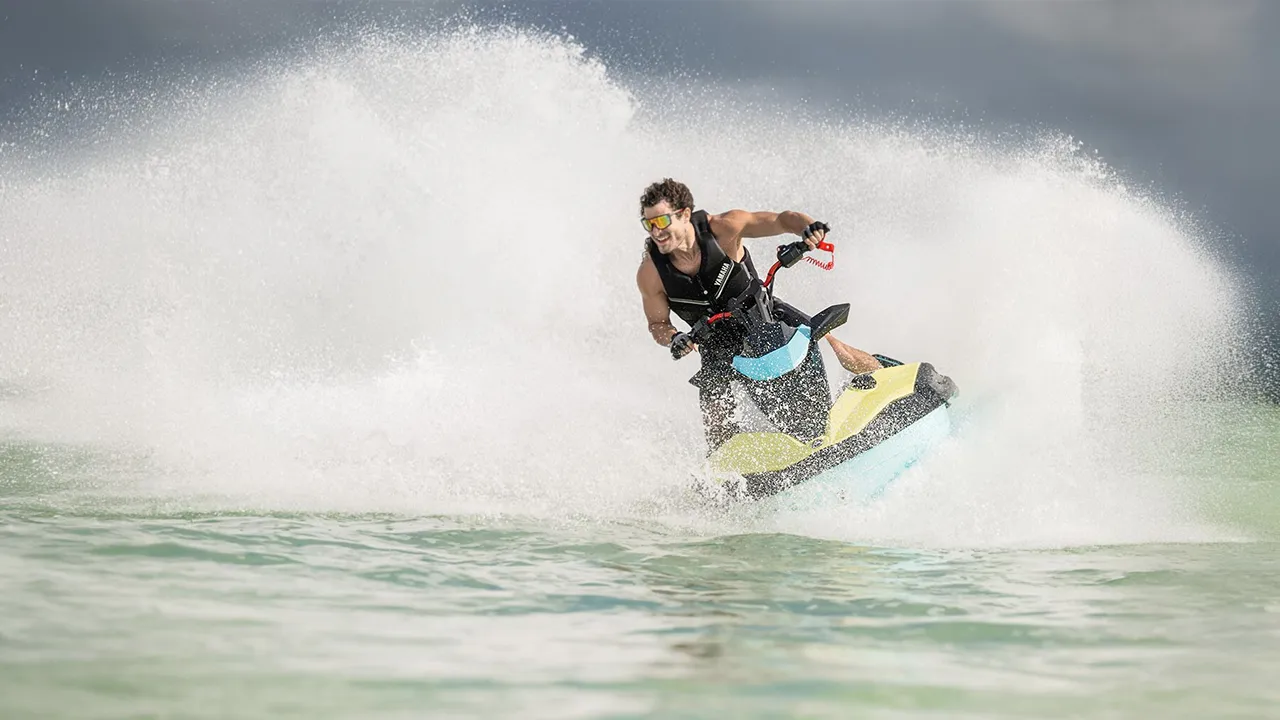 Man speeding on a yellow and turquoise jet ski