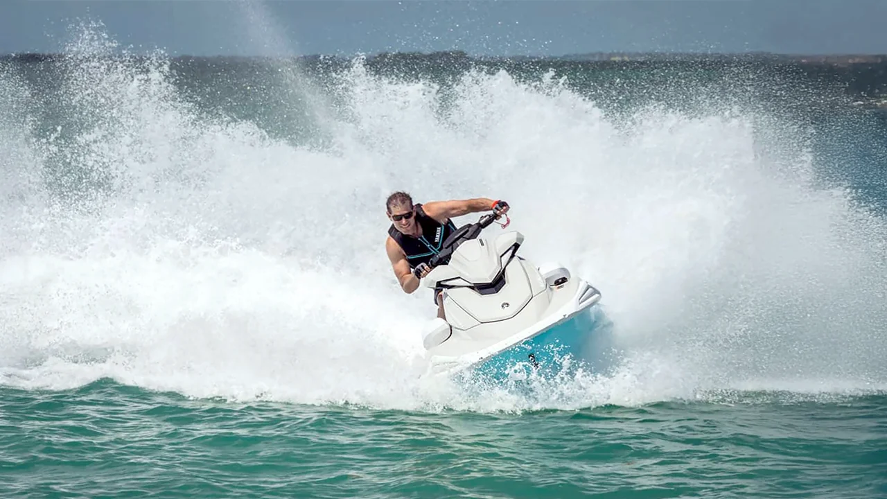 Man speeding on a turquoise and white jet ski