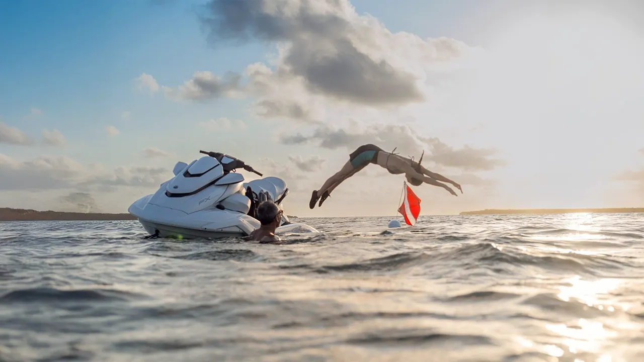 Woman diving off of a stationery jet ski