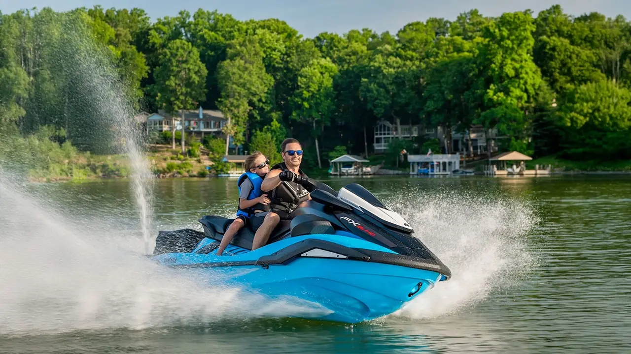 Man and young boy racing on a cyan jet ski