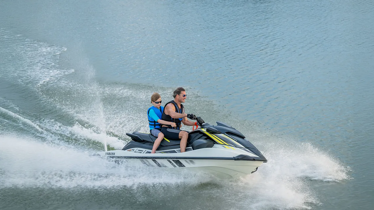 Man and boy racing on a white and black jet ski